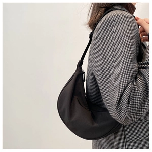 Side view of black nylon crescent moon shoulder bag worn with a houndstooth blazer