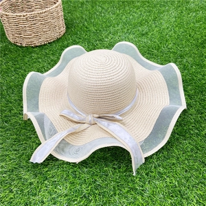 Détail du chapeau de soleil en paille avec bordure en dentelle et nœud en ruban gris chic