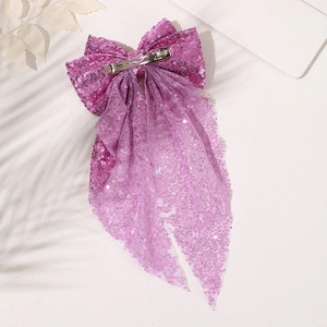 Close-up of purple sequin bow hair clip with tassel and metallic silver spring fastener