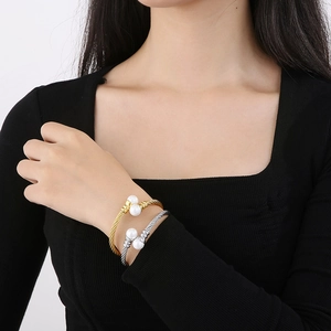 Detail of twisted cable cuff bracelets with elegant pearl accents on a female wrist