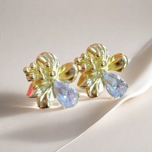 Micro-pave zircon flower earrings with blue teardrop stones in a gold plated finish