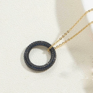 Detailed shot of 14K gold plated circular pendant featuring micro-set dark blue stones