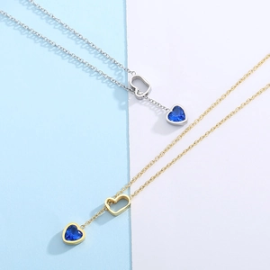 Detail view of gold and silver Y-necklaces with blue heart gemstone and hollow charms