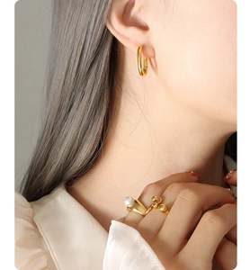 Detailed view of 18K gold-plated U-shaped earrings and an irregular pearl ring on model