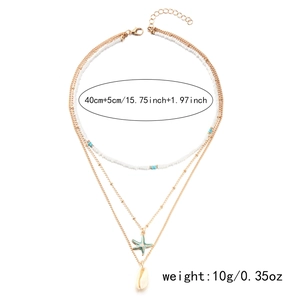 Détail d'un collier doré multicouche avec étoile de mer bleue et coquillages blancs