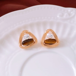 Detail of vintage twisted gold earrings with white pearl and tiger eye stone inlay