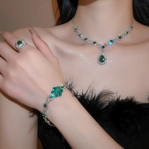 Close-up of luxury jewelry set with green gemstones and diamonds on a model