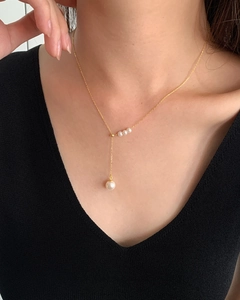 Detailed view of elegant s925 gold tassel necklace with white pearls on a model
