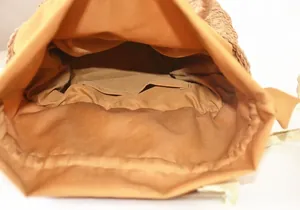 Detail view of the straw bag interior featuring a mustard fabric lining and inner pocket