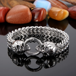 Detailed view of punk skull link chain bracelet on dark reflective surface with stones