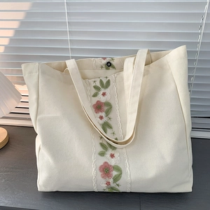 Dettaglio ricamo floreale su borsa tote in tela color crema con chiusura magnetica