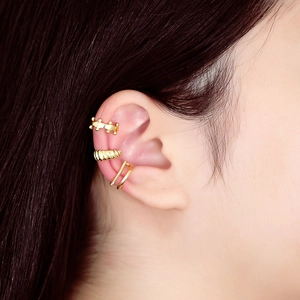 Close-up of three vintage gold metal ear cuffs with beaded and ribbed textures