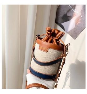 Detail of retro canvas bucket bag featuring leather trim and adjustable drawstring closure