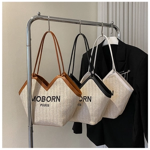 Detail of woven straw bucket bags with scalloped edges and MOBORN PARIS print on a rack