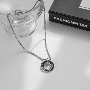 Detailed shot of interlocking triple ring pendant on box chain over glass bowl