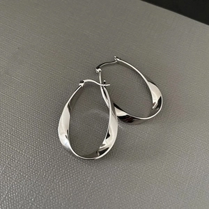 Macro shot of silver twisted hoop earrings with a polished metallic finish on leather