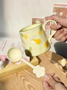 Detail of a yellow ceramic pineapple mug with a star-shaped spoon in a cozy setting