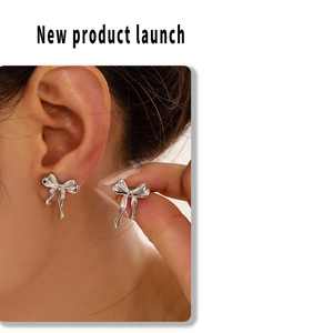 Close-up of silver bow stud earrings worn by a model showing size and elegant metal texture