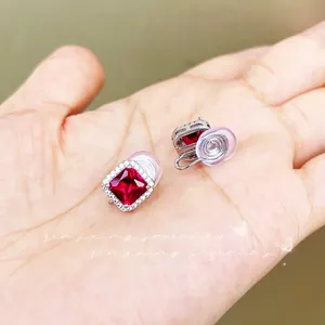 Macro detail of square ruby stud earrings with halo diamonds and comfort clip-on pads