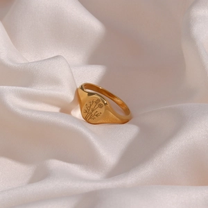 Gold stainless steel signet ring with engraved sunflower pattern on white silk background