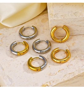 Detailed view of 4mm gold and silver stainless steel hoop earrings on a textured stone surface