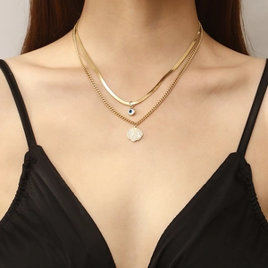 Double-layered gold snake chain necklace with heart pendant and shell charm on female model