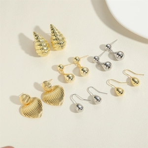 Flat lay of multiple minimalist gold and silver earrings with various geometric textures
