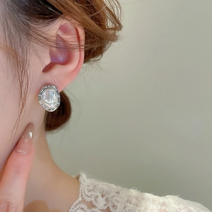 Close-up of irregular baroque pearl earring with silver trim worn by a model