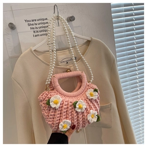 Detail of pink crochet shell bag with daisy flowers and elegant pearl bead strap