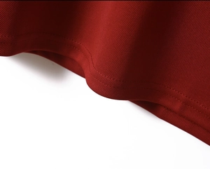 Detailed close-up of red polo shirt featuring breathable mesh fabric and double-stitched hem