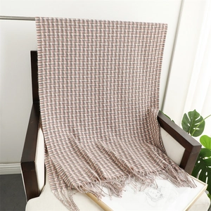 Detail of pink and grey plaid scarf with soft fringe texture on wooden chair