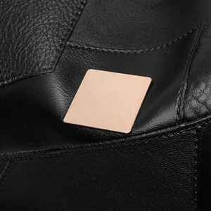Close-up of black leather texture and rose gold square metal hardware on commuter backpack