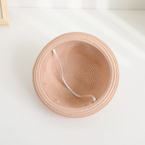 Detailed interior view of a pink straw hat for children featuring a white elastic chin strap
