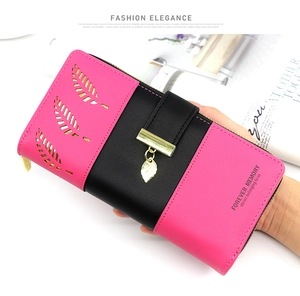 Detail of pink and black long wallet featuring hollow gold leaf patterns and metal pendant