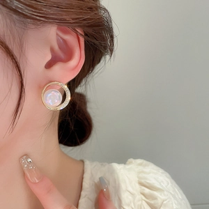 Gros plan détaillé de boucles d'oreilles créoles dorées avec perle sirène et zircons