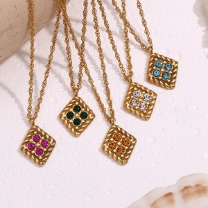 Detailed macro of gold geometric diamond necklaces with colorful stones on watery surface