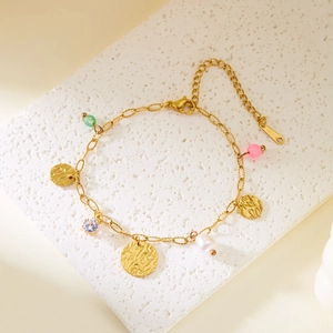 Détail du bracelet à breloques en or avec perles et zircon sur support en pierre