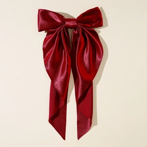 Close-up of a large wine red satin bow hair clip with glossy silk texture details