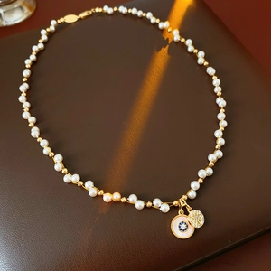 Detail of a pearl necklace with star and blue gemstone charms on brown leather