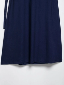 Detail view of navy blue pleated skirt hem showing plain fabric texture and draping