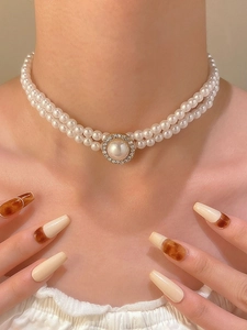 Detail of a double-layered white pearl necklace with a gold zircon pendant on model