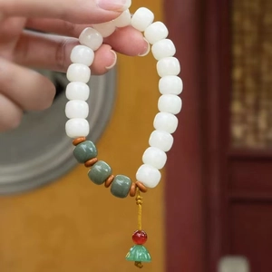 Detail of beaded bracelet with green tassels and jade-like beads on a vintage background
