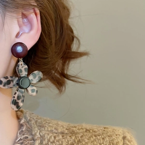 Detail of vintage flower drop earrings with leopard print petals on a female model