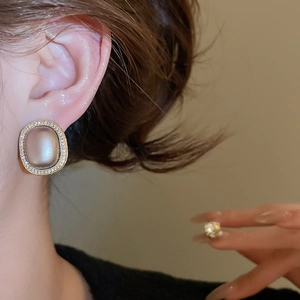 Close-up of elegant gold vintage stud earrings with champagne pearl and pavé diamonds