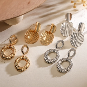 Minimalist geometric knot earrings in gold and silver finish with textured oval pendant