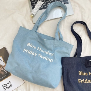 Dettaglio delle lettere ricamate sulla borsa tote in denim blu con grande capacità