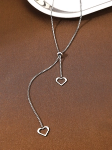 Detailed macro view of silver Y-shaped adjustable necklace with hollow heart pendants