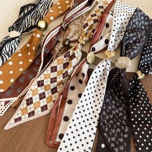 Close-up of silk scarves with polka dot and zebra patterns featuring gold metal buckles