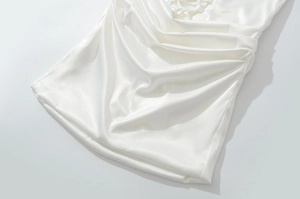 Dettaglio di un abito in raso bianco con pieghe arricciate e texture lucida