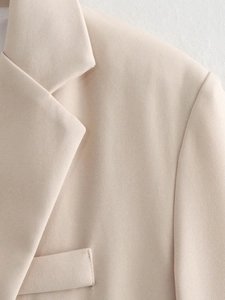 Detail shot of beige blazer lapel and pocket showing high-density twill fabric texture